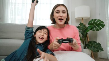 Kafkas anne ve kızı oturma odasında oturup oyun oynuyorlar. Mutlu anne, elinde joystick tutarken akıllı Asyalı kızla vakit geçiriyor. Oyun oynamaktan zevk alıyor. Yaşam tarzı konsepti. Pedagoji.