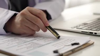 Hastanedeki doktor masasında oturup hasta test sonuçlarını teşhis eden, hastalıklar ve hastalıklar için tedavi planı geliştiren evrak işleriyle uğraşıyor. Sağlık personeli ve sağlık hizmetleri. Ağır çekim. Katı.