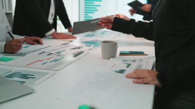 Etkileşimli bir toplantıya katılan dinamik bir iş adamı grubu, çeşitli veri tablolarını analiz ediyor ve gelecekteki başarı için strateji oluşturmaya çalışıyor. SACTR