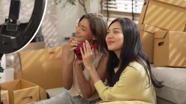 Satıcı çevrimiçi platformu kullanarak canlı yayın yaparken ürünü incelemek ve satmak için birlikte çalışıyor. Zeki Asyalı girişimci soruları cevaplarken ürün gösteriyor. Medya. Yan görüş. Myrmidon.