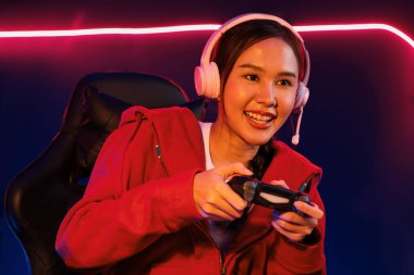 Oyun çubuğu ile gülümseyen Asyalı güzel kız flamasının sunucu kanalı kulaklık yapıştırıcısı takarak online izleyici medyasıyla konuşuyor. Esport yetenekli takım oyuncuları neon odada. Taktik.