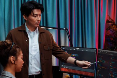 Bilgi teknolojisi geliştiricileri modern ofisteki neon ışık odasında verileri çevrimiçi olarak çalıştıran akıllı web sitesi geliştirme kodlayıcı sistemine işaret ediyorlar. İnfobahn.