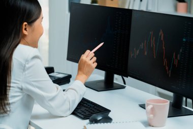 Modern ofisteki borsa grafiğinin kârını analiz etmek için bilgisayara bakan genç ve güzel Asyalı bir iş kadını. Finans sektöründe refah güvenliğine yüksek kâr yatırımı kavramı. Taktik.
