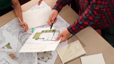 Mimari döküman, ölçüm araçları ve ahşap blokların modern ofiste etrafa saçıldığı masa üzerine planlar yapma konusunda akıllı mimar ve güvenlik mühendisi tartışması. - Yakın çekim. Tanımlama.