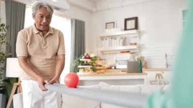 Yaşlı bir adam evde partneriyle top yuvarlama oyunu oynuyor, zihinsel ve fiziksel sağIık için el-göz koordinasyonu, odaklanma ve motor becerileri pratiği yapıyor. Sağlık hizmetleri konseptini engelliyor. Myrmidon.