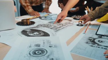 Profesyonellerden oluşan dinamik bir ekip, teknik çizimler, araçlar ve tasarım planlarıyla dolu bir masa etrafında ortak bir tartışmaya girişiyor ve yaratıcı takım çalışmalarını sergiliyor. SACTR