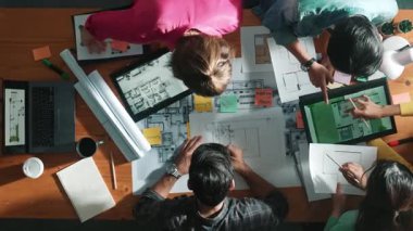 Yöneticinin proje planı yazması ve toplantıda oturması. Bilgisayarlı ve teçhizatlı ev inşaatı hakkında planlar yapan ve paylaşan iş adamlarının havadan görüşü. Sempozyum.