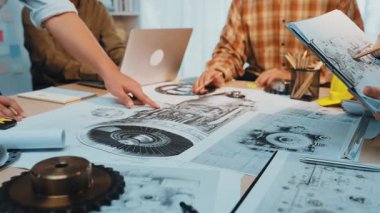 Çeşitli profesyonellerden oluşan bir ekip, modern bir ofiste detaylı teknik çizimler üzerine beyin fırtınası ve işbirliği yaparak yaratıcılık ve yenilik sergiliyor. SACTR