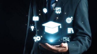 Sivri takım elbiseli bir işadamı, elinde parlak eğitim simgelerini, modern öğrenme ve profesyonel gelişimi sembolize eden karanlık bir geçmişe karşı gösteren bir akıllı telefon tutuyor. Dörtgen