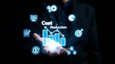 Bir işadamı, dinamik bir kurumsal ortamda yenilik ve stratejik yönetimi vurgulayarak, maliyet azaltma ve mali büyümeyi sembolize eden dijital simgeler sergiliyor. Dörtgen