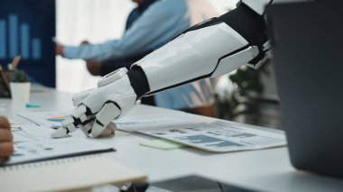 Bir robotik kol modern çalışma alanındaki iş analistleriyle etkileşime girer, veri analizinde işbirliğini vurgular ve teknoloji yoluyla verimliliği artırır. Noogenesis