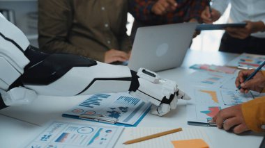 Bir robot kol, dinamik ofis ortamında insan meslektaşlarıyla etkileşime girer, verileri analiz eder ve çağdaş bir çalışma alanı üzerinde yenilikçi stratejiler geliştirir. Noogenesis