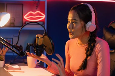 Geceleri podcast 'te olumlu konuşmalar yapan, pembe neon ışıklı modern stüdyoda sunum için dizüstü bilgisayar kullanan, gülümseyen, genç, güzel Asyalı bir etkileyiciydi. Taktik.