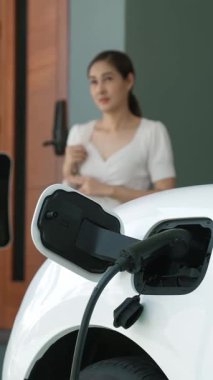 Bir kadın evinde elektrikli araç şarj aletinin fişini çekiyor. İlerici bir yaşam tarzında elektrikli araçların kullanımı, temiz ve sağlıklı bir çevreye katkıda bulunur..