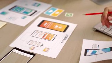 Mobil uygulama için kullanıcı arayüzü prototipini ofis çalışanlarına sunan harika bir şirket çalışanı. UX UI tasarımcısı kağıt üzerinde simge tasarımının işlevini açıklıyor. Sinerjik