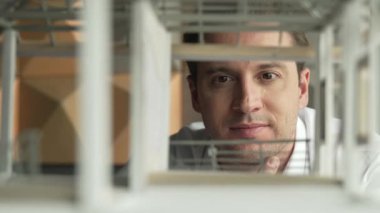 Kafkasyalı mimar mühendisinin yakın çekimi ev inşaatını denetlemek ve bina malzemelerini kontrol etmek. Proje yöneticisi modele dikkatlice bakarken kalemi işaret ediyor. Yönlendirici.