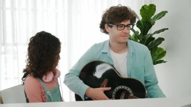 Beyaz bir baba gitar çalar ve müziğe yönelirken Amerikalı kız da akustik şarkı eşliğinde el sallar ve dans eder. Mutlu aile evde birlikte vakit geçirir. Yaratıcı aktivite konsepti. Yaşam tarzı. Pedagoji.
