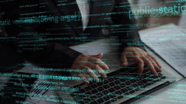 Yazılım geliştirme ve teknolojinin özünü modern bir çalışma alanında temsil eden programlama metinleriyle çevrili bir dizüstü bilgisayarda elle yazma koduna odaklanmış bir bakış. Xenic