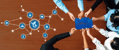 Takım üyeleri, grafiksel iş simgeleriyle çevrili bir yapbozu tamamlarken, başarı için takım çalışmasını ve stratejik planlamayı sembolize eden ahşap bir masa üzerinde işbirliği yapıyorlar. Dostluk