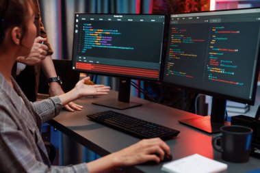 Bilgi teknolojisi geliştiricileri modern ofisteki neon ışık odasında verileri çevrimiçi olarak çalıştıran akıllı web sitesi geliştirme kodlayıcı sistemine işaret ediyorlar. İnfobahn.