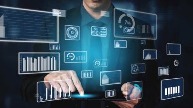 Bir işadamı, çeşitli veri görselleştirmelerini gösteren dijital arayüzlerle etkileşime girerek, veri analizinin ticari büyüme ve yenilik açısından önemini vurguladı. Xenic