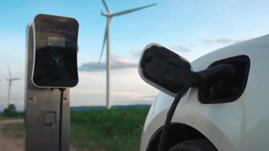 Çevreyi korumak için rüzgar türbininden yeşil ve yenilenebilir enerjiyle çalışan şarj istasyonunda şarj edilen gelişmiş gelecek enerji altyapısı konsepti.