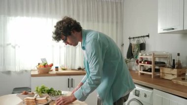 Mutlu baba yemek pişirirken müziğe geçiyor ve modern mutfakta öğle yemeği hazırlıyor. Aktif baba, sebze ve mutfak gereçleri ile çevrili sağlıklı yemek ya da salata yaparken şarkıyla dans ediyor. Pedagoji.