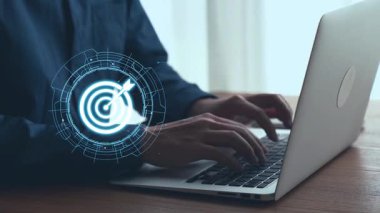 Modern iş planlaması ve analizini temsil eden hedef simge ve grafiklerin yer aldığı dijital pazarlama stratejisi ile dizüstü bilgisayarda yazı yazan ellerin yakın görüntüsü. Dörtgen