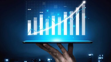 Finansal büyüme ve piyasa eğilimlerini gösteren dijital grafikleri gösteren bir tablet, gösterişli bir gece iş zeminine karşı hazırlanıyor. Copula