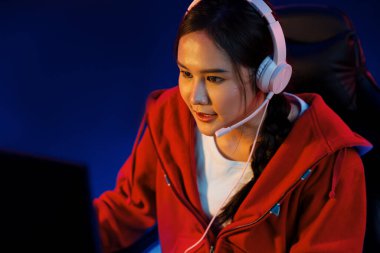 Portre sunucusu güzel Asyalı kız flamasının çevrimiçi oyun oynaması kulaklık takması pastel renkli konuşmalar izleyici medyası ile çevrimiçi. Esport yetenekli takım oyuncuları neon mavi odada. Taktik.