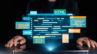 Bir programcı, karanlık bir ortamda bir dizüstü bilgisayarın üzerinde canlı dijital kod grafikleriyle etkileşime geçerek modern programlama dilleri ve teknolojik yenilikler sergiliyor. Dörtgen