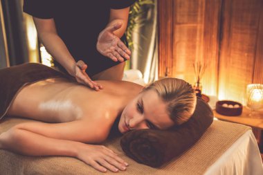 Beyaz kadın müşteri stres önleyici spa masajının keyfini çıkarıyor ve lüks otel ya da otelde sıcak mum ışığında güzellik teniyle eğleniyor. Sessiz.