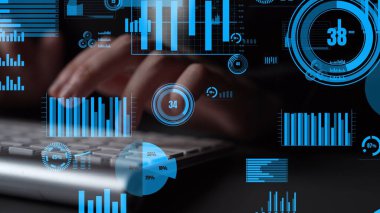 Dijital grafikler ve istatistiklerin arka planına karşı klavyede yazı yazan ellerin yakın plan görüntüsü, veri analizi ve teknolojiye çağdaş bir yaklaşım sergiliyor. Xenic