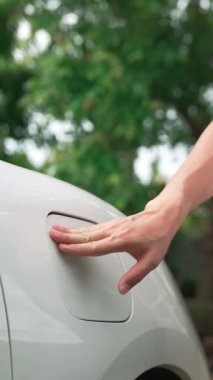 İlerici adam elektrikli aracına elektrik kablosu takıyor. Ev şarj istasyonundan EV arabası. Çevreyi korumak için temiz ve yenilenebilir enerji kullanan elektrikli bir araba. Çevre dostu otomobil.