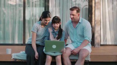 Sevimli baba, anne ve kızı birlikte evin dışındaki balkonda oturuyorlar. Ebeveynler, çevre farkındalığıyla ilgili genç nesli iletişim kurmak için açık hava aktivitelerini kullanırlar. Uyumsuzluk.