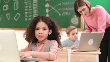 Çekici kız kodlama hızlı BTMM sınıfında kameraya bakarken mutlu öğretmen akıllı çocuk yazılım programını kontrol ediyor. Programlama kodu ve bilgisayar sistemi üzerine çeşitli öğrenci çalışmaları. Pedagoji.