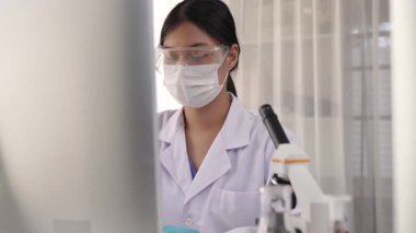 Laboratuvar kimya araştırmacısı mikroskop ve dizüstü bilgisayar kullanarak yeni ilaç ya da tedavi geliştirir. Bilimsel uzmanlığa ve laboratuvar mikrobiyoloji ekipmanlarına sahip sağlık teknolojisi. Ağır çekim. Katı.