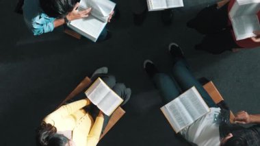 İncil 'i okuyup, kucağında İncil' le daireler çizerek otururken en tepeden aşağı dua manzarası. İnanç, güven ve umut ve sükunetle çalışırken farklı insanların kitaba bakışları. Sempozyum.