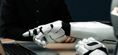 Gelecekçi bir robotik kol, gelişmiş teknolojinin ve modern bir çalışma alanı düzenindeki insan benzeri etkileşimin karışımını vurguluyor. Noogenesis