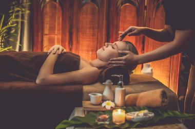 Beyaz kadın stres önleyici kafa masajı yapmaktan ve lüks otel veya otelde sıcak mum ışığında yüz güzelliği eğlencesi yapmaktan zevk alıyor. Sessiz.