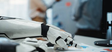 Robot bir elin modern bir ofisteki iş belgeleriyle etkileşime girerek iş yerindeki teknoloji ve otomasyonun entegrasyonunu gösteren yakın plan görüntüsü. Noogenesis