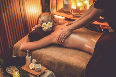 Beyaz kadın müşteri stres önleyici spa masajının keyfini çıkarıyor ve lüks otel ya da otelde sıcak mum ışığında güzellik teniyle eğleniyor. Sessiz.