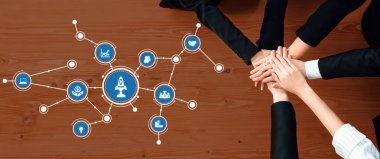 Çeşitli bir iş ekibi işbirliği içinde birleşerek modern hedef belirleme ikonlarının üzerinde ellerini birleştiriyor, yenilikçiliği, başarıyı ve ileri görüşlülüğü sembolize ediyor. Dostluk