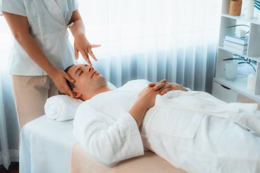 Beyaz adam stres önleyici kafa masajından ve lüks bir tatil beldesi veya otel spa salonundaki modern ışık ortamında yüz güzelliği eğlencelerini şımartmaktan hoşlanıyor. Sessiz.
