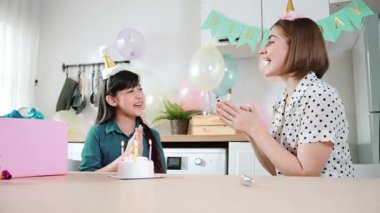 Enerjik kız ve anne birlikte müzik eşliğinde doğum günü şarkısı söylüyorlar. Kafkasyalı anne doğum gününü yemek odasında renkli balonla süslenmiş pastayla kutladı. Pedagoji.