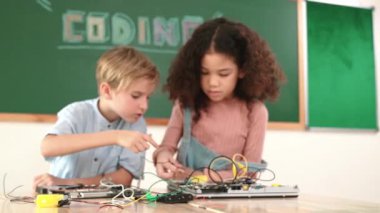 Kız tornavida kullanarak elektronik tahtayı tamir ederken ayakta duruyor. Amerikalı öğrenci ve beyaz çocuk elektrik sistemini denetlemek için birlikte çalışıyorlar. Gemide çalışan meraklı çocuklar. Pedagoji.