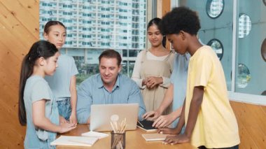 Başarılı bir proje için öğrencileri teşvik etmek ya da kutlamak için yetenekli bir öğretmen alkışlıyor. Çeşitli çocuklar profesyonel eğitmenin etrafında dururken el çırpıyorlar. Öğretim