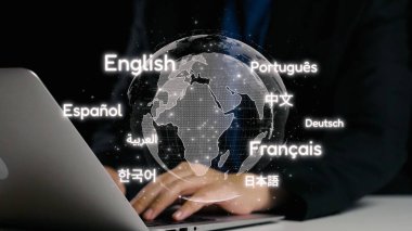 Yukarıda parlayan bir dünya haritası olan dizüstü bilgisayarda yazı yazan ellerin yakın çekim görüntüsü, birden fazla dilin sergilenmesi, iş ve eğitim alanında küresel iletişimi temsil ediyor. Dörtgen