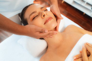 Kafkasyalı kadın stres önleyici kafa masajından ve lüks tatil beldesi ya da otel spa salonundaki modern ışık ortamında yüz güzelliği eğlencelerini şımartmaktan hoşlanıyor. Sessiz.