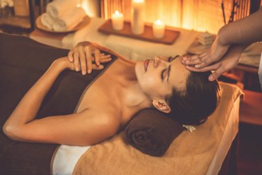 Beyaz kadın stres önleyici kafa masajı yapmaktan ve lüks otel veya otelde sıcak mum ışığında yüz güzelliği eğlencesi yapmaktan zevk alıyor. Sessiz.